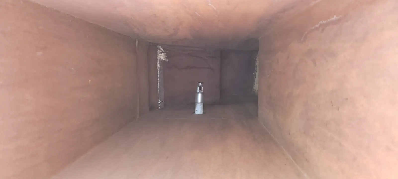 Looking down the inside of a cleaned sheet-metal duct run toward the light at the far end